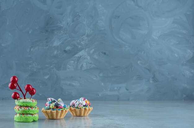 Cupcakes avec garnitures de bonbons et petits beignets sur fond de marbre. Photo de haute qualité