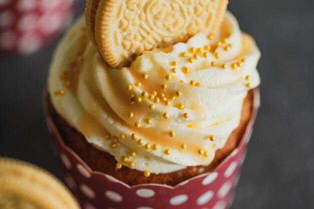 Cupcakes à la vanille avec crème et caramel sur fond de table gris.