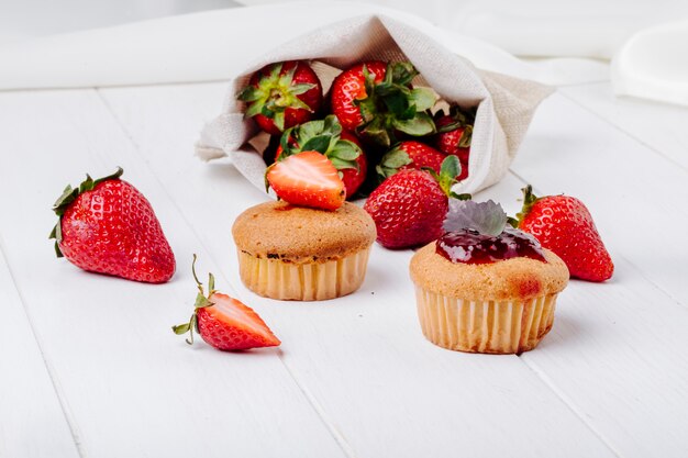 Cupcakes vue de côté avec de la confiture de fraise basilic et fraise fraîche sur fond blanc