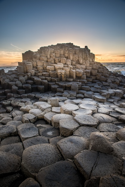 Photo gratuite curieuse formation rocheuse avec des segments hexagonaux à côté d'un plan d'eau