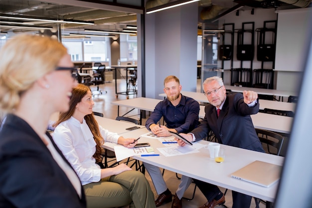 Curieux doigt mature homme d&#39;affaires pointant au tableau à feuilles mobiles dans la présentation