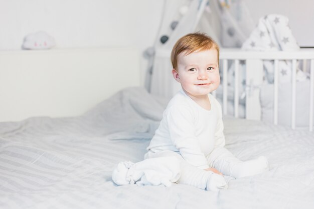 Cute blonde bébé dans un lit blanc