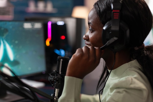 Cyber woman gamer parlant dans le microphone pendant la diffusion en direct tout en jouant à des jeux vidéo en ligne pendant le championnat de tir spatial. Joueur d'esport utilisant un équipement informatique RBG. Tournoi de sport électronique