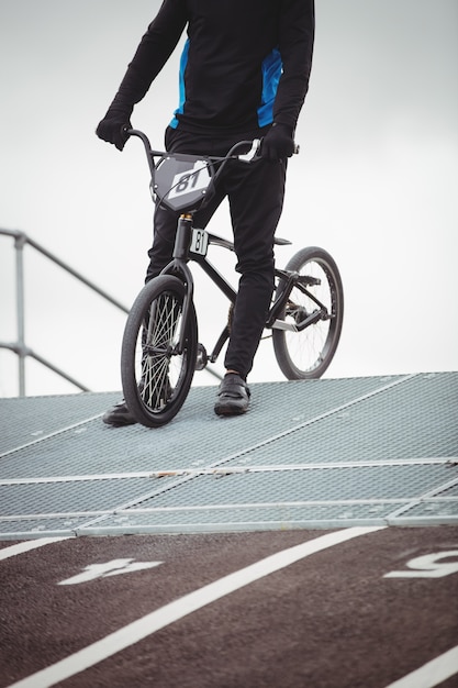 Cycliste debout avec vélo BMX sur la rampe de départ