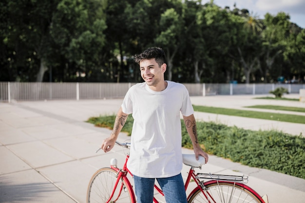 Photo gratuite cycliste heureux posant devant sa bicyclette