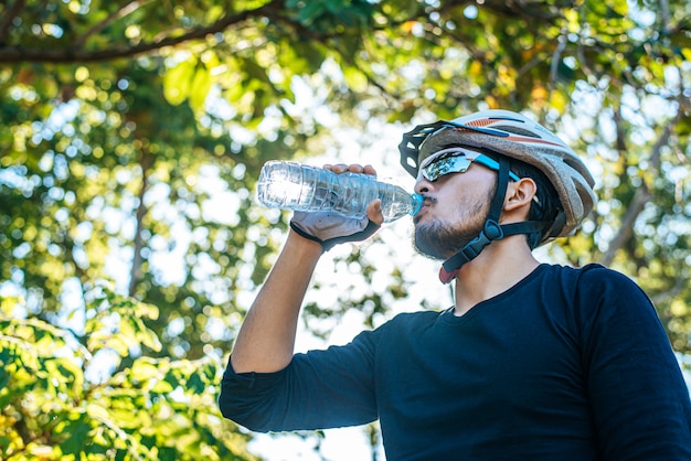 Les cyclistes de montagne se tiennent sur le sommet de la montagne et boivent une bouteille d'eau.