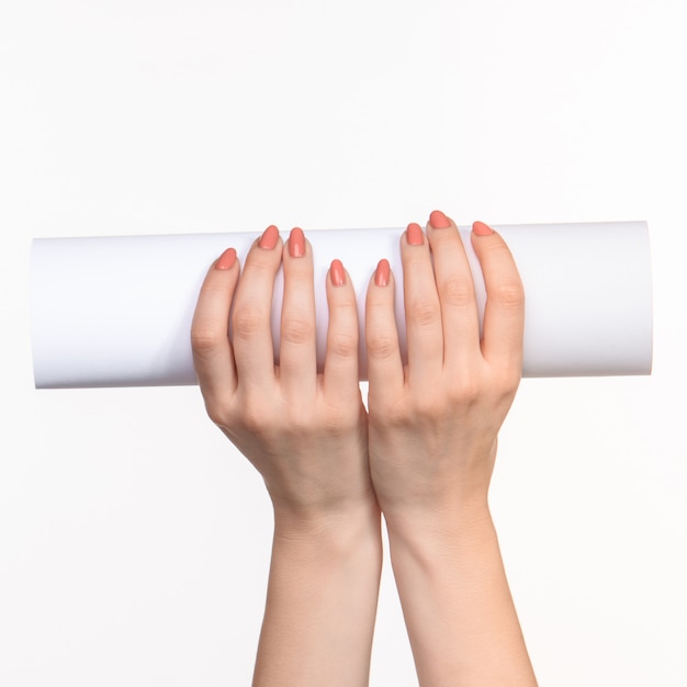 Le cylindre blanc des accessoires dans les mains féminines sur blanc avec ombre droite