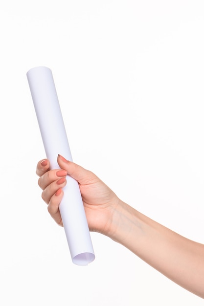 Le cylindre blanc des accessoires dans les mains féminines sur fond blanc avec ombre droite