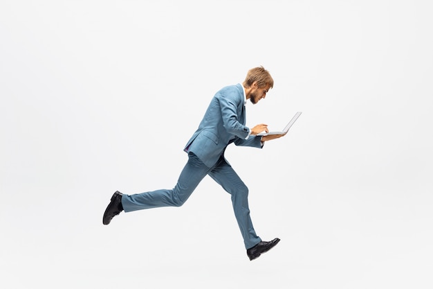 Dactylographie. Homme en tenue de bureau en cours d'exécution, jogging sur un espace blanc comme athlète professionnel, sportif. Look inhabituel pour homme d'affaires en mouvement, action avec ballon. Sport, mode de vie sain, créativité.