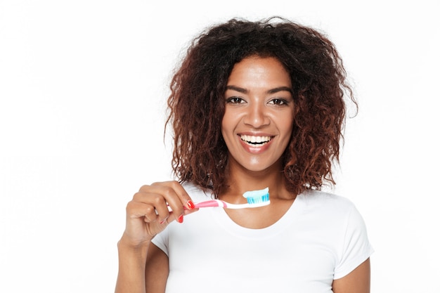 Dame africaine tenant une brosse à dents avec du dentifrice.