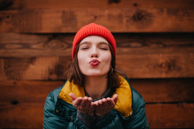 Dame au chapeau rouge envoie un baiser aérien les yeux fermés