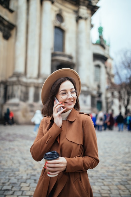 Photo gratuite dame aux cheveux courts en chapeau léger parler sur phote et messages texte sur son téléphone