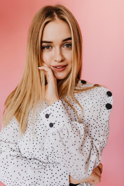 Dame aux yeux verts en blouse blanche regardant la caméra avec intérêt Studio photo d'un modèle caucasien sensuel