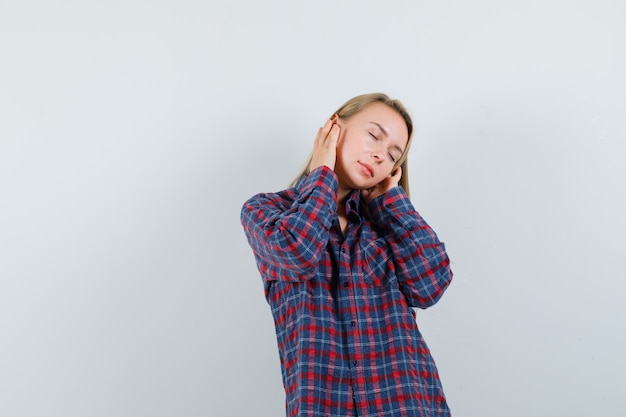 Dame blonde en chemise décontractée faisant semblant d'écouter de la musique et à la vue de face, paisible.