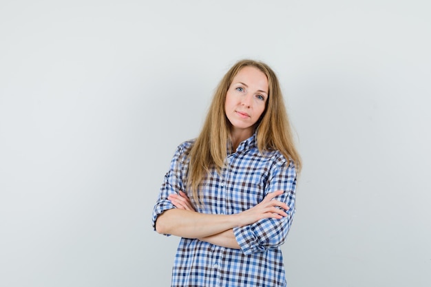 Dame blonde debout avec les bras croisés en chemise et à la confiance,