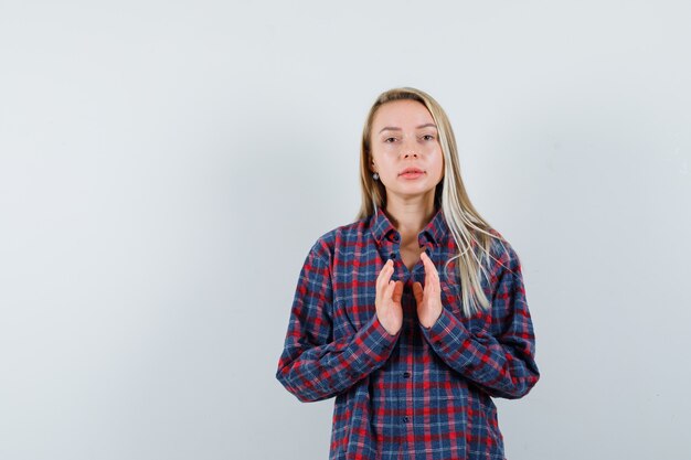 Dame blonde faisant semblant de garder quelque chose en chemise décontractée et à la vue de face, confiant.