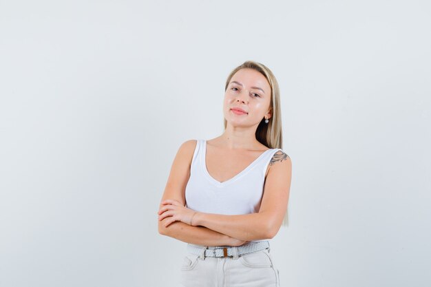 Dame blonde en maillot, pantalon debout avec les bras croisés et à la confiance