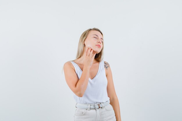 Dame blonde en maillot, pantalon touchant son menton et à l'air détendu