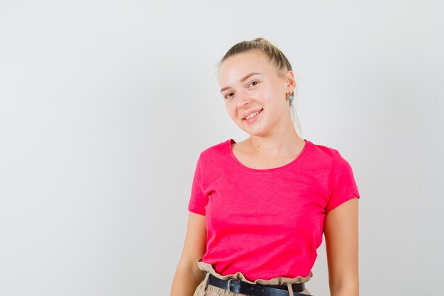 Dame blonde en t-shirt, pantalon et à la recherche joviale. vue de face.