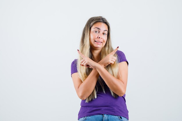 Dame blonde en t-shirt violet, jeans pointant vers l'extérieur, vue de face.