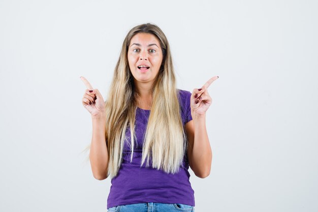 Dame blonde en t-shirt violet, jeans pointant vers l'extérieur, vue de face.