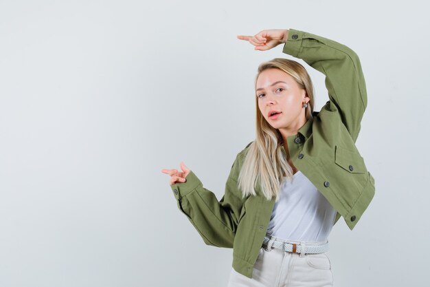 Dame blonde en veste, pantalon pointé de côté et à la jolie vue de face.