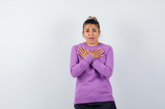 Dame en blouse de laine tenant les mains sur la poitrine et à la perplexité