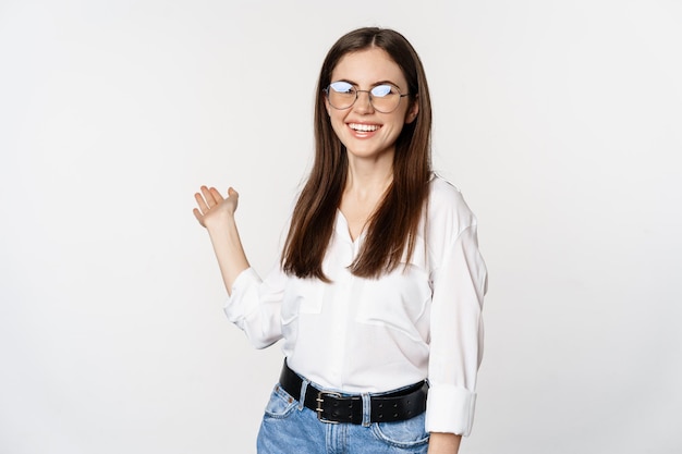 Dame de bureau femme brune souriante montrant la voie pointant derrière la démonstration de qch derrière son standin ...