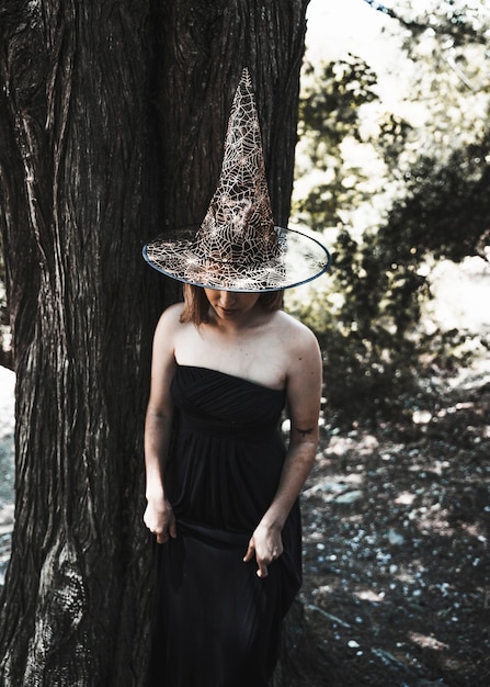 Dame en costume de sorcière debout près de l&#39;arbre