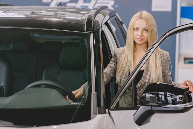 Dame dans un salon de voiture. Femme achetant la voiture. Femme élégante dans un costume marron.