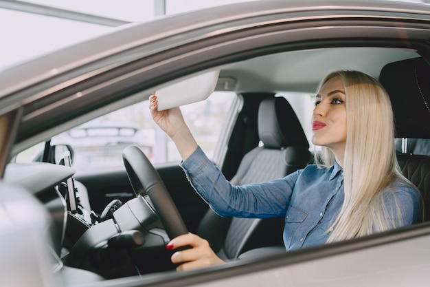 Dame dans un salon de voiture. Femme achetant la voiture. Femme élégante dans une robe bleue.