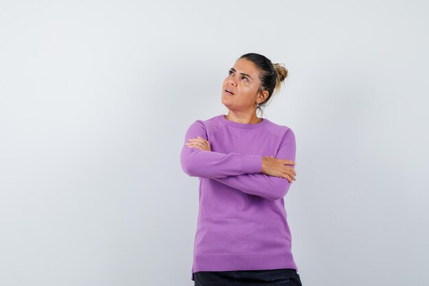 Dame debout avec les bras croisés en blouse de laine et à la pensive