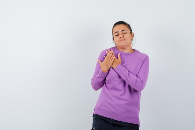 Dame gardant les mains sur la poitrine en chemisier en laine et l'air calme