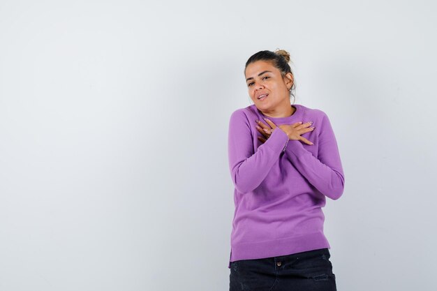 Dame gardant les mains sur la poitrine en chemisier en laine et ayant l'air mignon