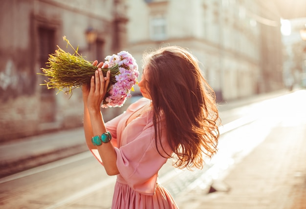 Une dame impressionnante en robe rose pose dans les rayons du soleil du matin sur le