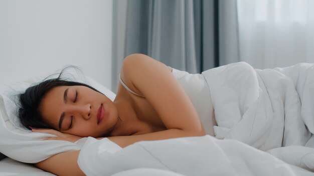 Dame indienne asiatique dormir dans la chambre à la maison. Jeune fille asiatique se sentir heureux se détendre se trouvant sur le lit, se sentir à l'aise et calme dans la chambre à coucher à la maison au matin.