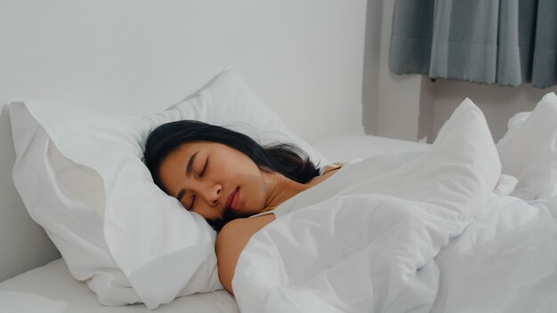 Dame indienne asiatique dormir dans la chambre à la maison. Jeune fille asiatique se sentir heureux se détendre se trouvant sur le lit, se sentir à l'aise et calme dans la chambre à coucher à la maison au matin.