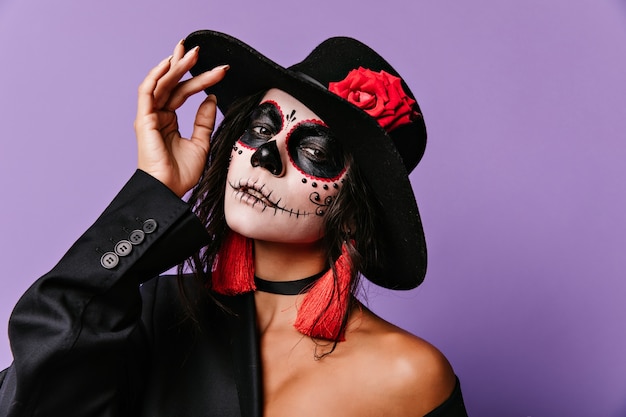 dame latine enthousiaste en tenue muertos. Photo intérieure d'une fille caucasienne inspirée portant un costume de zombie à l'halloween.