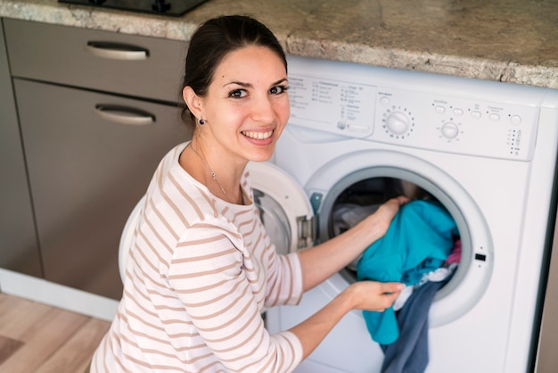 Photo gratuite dame mettant des vêtements dans la machine à laver