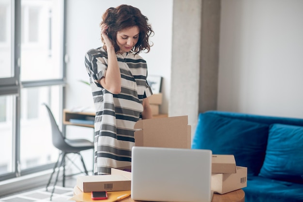 Dame occupée concentrée sur la préparation des marchandises pour l'expédition