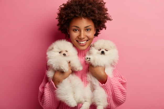 Dame à la peau foncée garde les lèvres arrondies, veut embrasser un animal adorable, joue avec un petit chiot