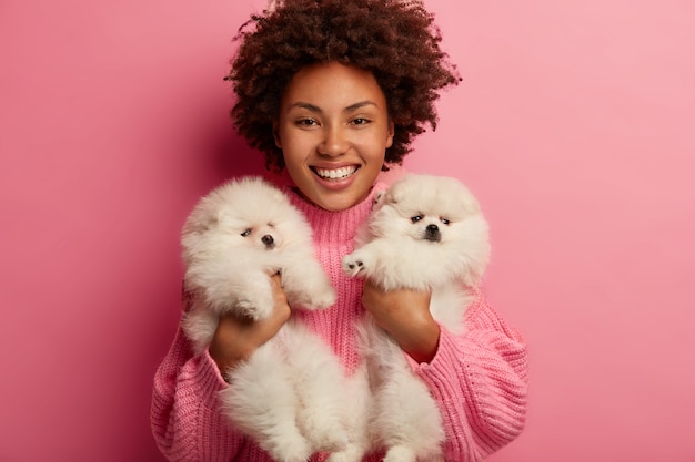 Photo gratuite dame à la peau foncée garde les lèvres arrondies, veut embrasser un animal adorable, joue avec un petit chiot