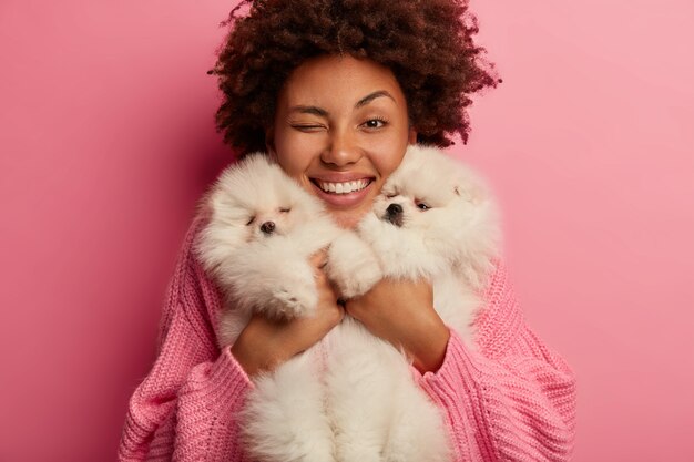 Dame à la peau foncée garde les lèvres arrondies, veut embrasser un animal adorable, joue avec un petit chiot