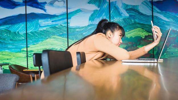 Dame prenant selfie près d&#39;un ordinateur portable à la table