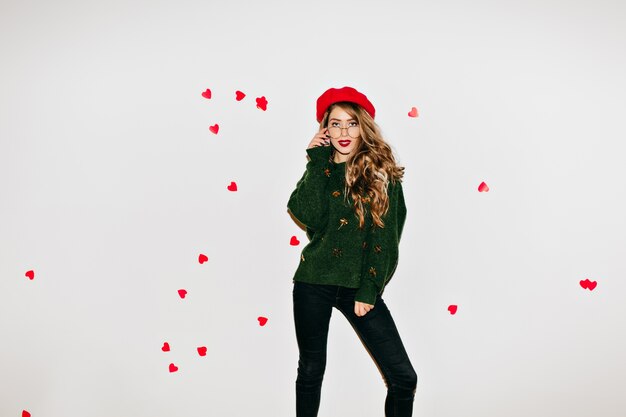 Dame de rêve en béret debout dans une pose confiante tout en posant dans la Saint-Valentin