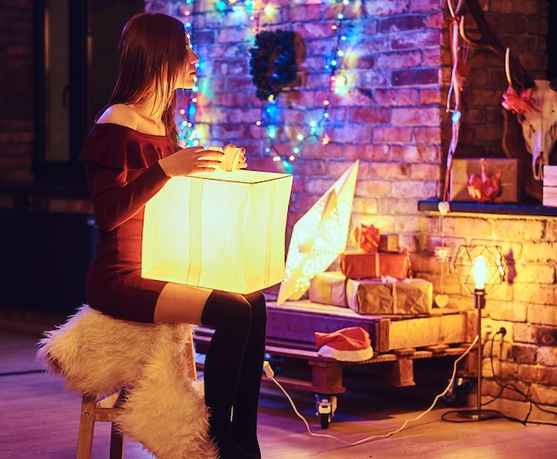 Dame sexy rousse posant dans une chambre avec intérieur loft et décoration de Noël.