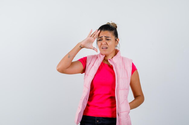 Dame en t-shirt, gilet gardant la main sur la tête et l'air triste