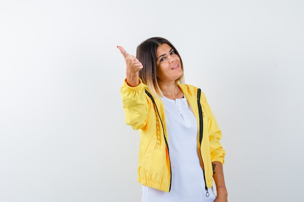 Dame en t-shirt, veste étirant la main et à la fierté, vue de face.