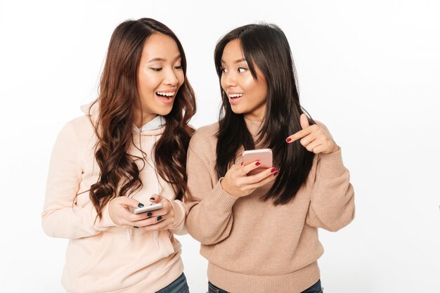 Dames asiatiques assez heureuses, discutant par téléphone mobile.
