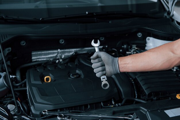 Dans la boutique. La main de l'homme dans la main tient la clé en face de l'automobile cassée